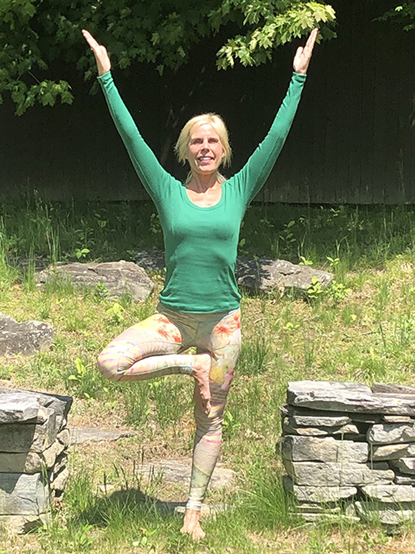 Kim Nashed in tree pose amid the lush foliage of her backyard